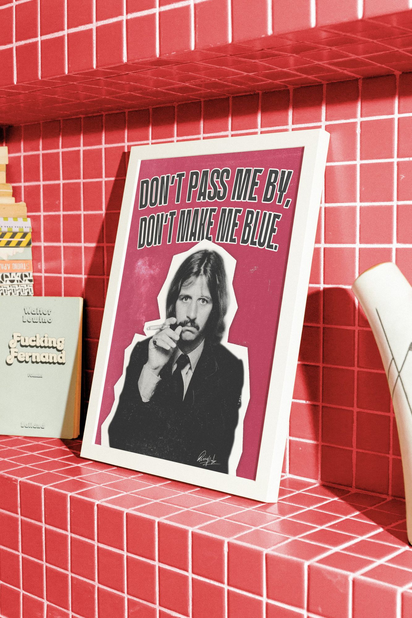 The Ringo Starr poster in a white frame on a red tiled shelf