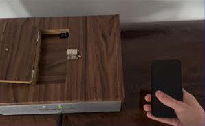 A hand holding a phone next to the open TuneVault hatch